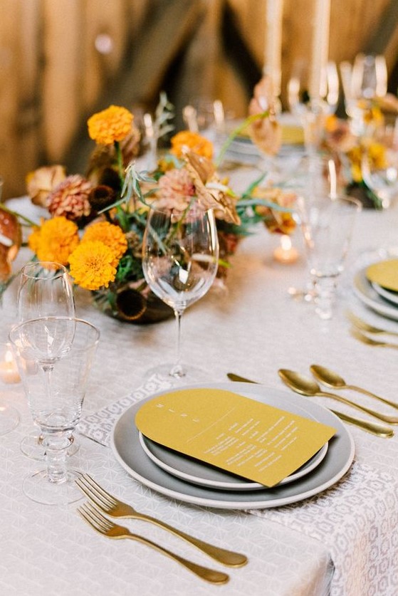 a retro-inspired bridal shower table setting done with mustard and grey touches, gold cutlery and bold centerpieces