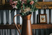 a rustic vintage wedding centerpiece of a dark metal jug and blush blooms and dahlias is a lovely idea for a vintage wedding