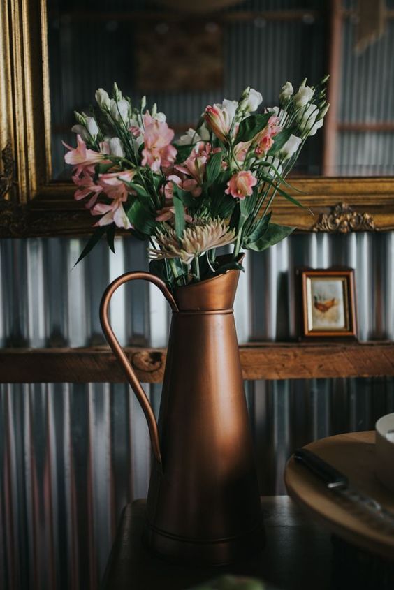 a rustic vintage wedding centerpiece of a dark metal jug and blush blooms and dahlias is a lovely idea for a vintage wedding