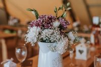 a simple rustic wedding centerpiece of a white jug and white and pink blooms is a pretty idea for a summer wedding