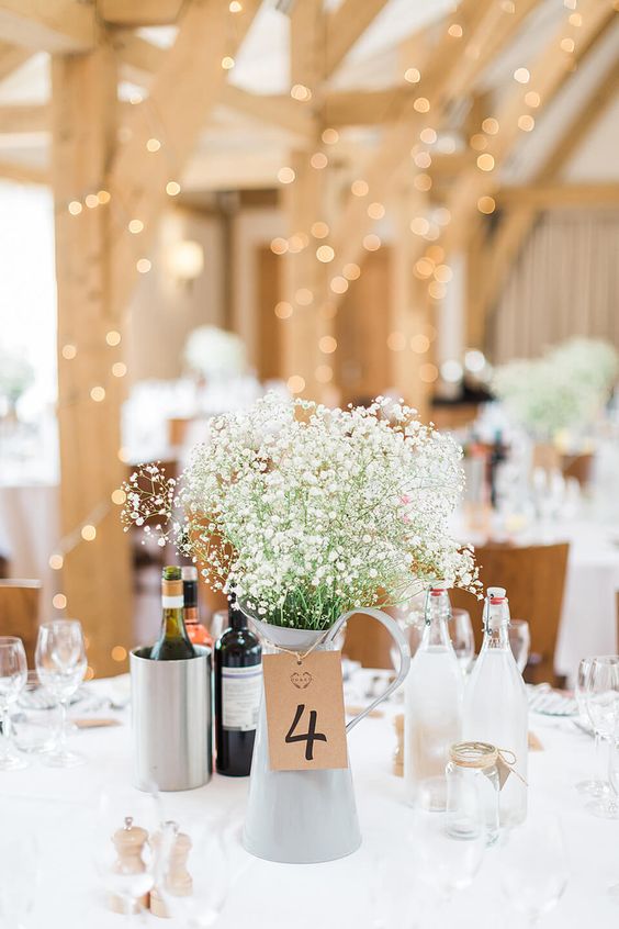 a super simple rustic wedding centerpiece of a metal jug with baby's breath and a cardboard tag is amazing for a rustic wedding