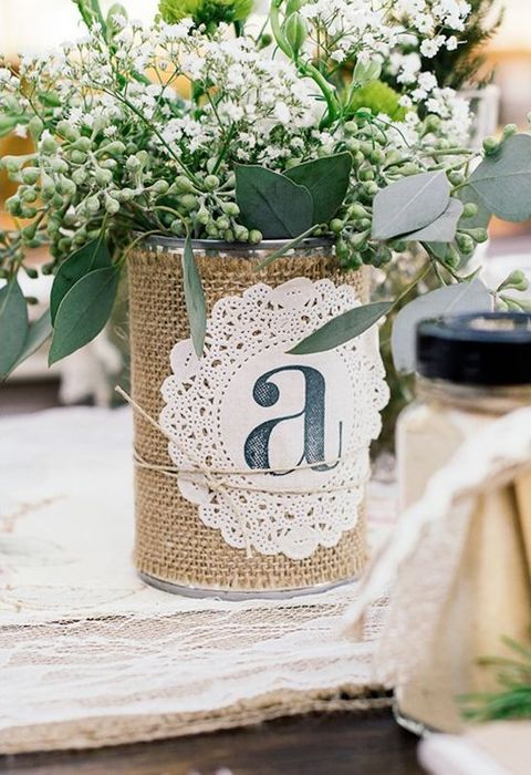 a tin can wrapped with burlap and with a doily, greenery and flowers for a centerpiece