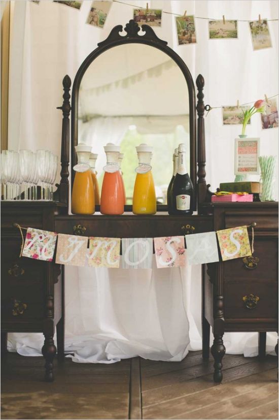 a vintage and rustic drink bar with a colorful floral bunting, juices and glasses for a chic look