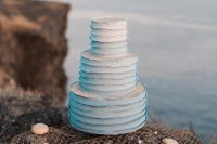 a white textural cake with blue ruffles displayed on fishing net with macarons and edible pearls is a great idea for your mermaid bridal shower