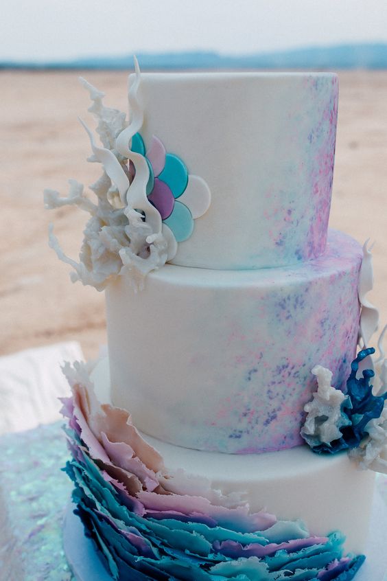 a white wedding cake with pink, purple and turquoise splashes, scallops, corals and ruffles is an amazing idea for your bridal shower