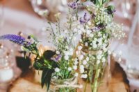 a wood slice with mason jars with wildflowers for a rustic centerpiece