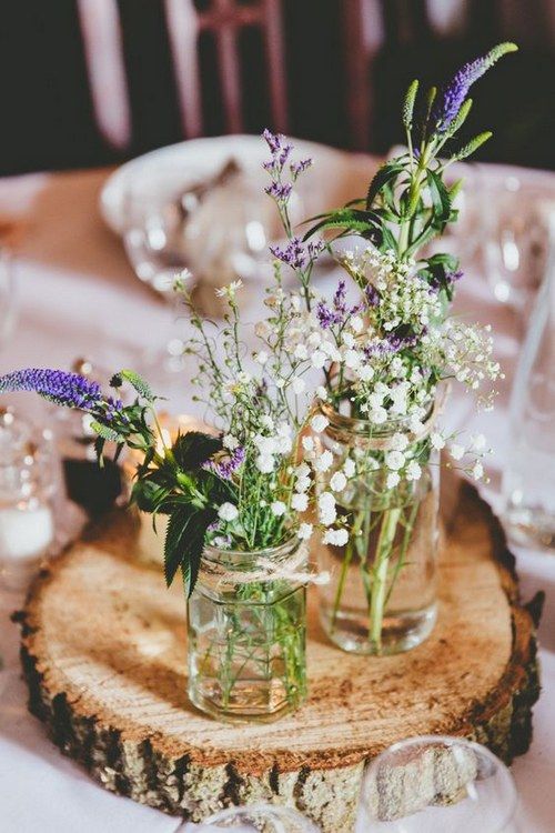 a wood slice with mason jars with wildflowers for a rustic centerpiece