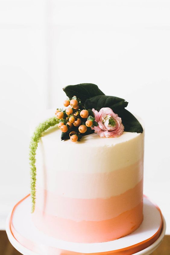 an ombre retro bridal shower cake with berries, pink ranunculus and greenery on top is a great idea for spring or summer