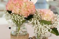 jars with hydrangeas and baby’s breath wrapped with burlap and placed on a wooden slice