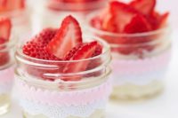 jars with lace and pink ribbons with fresh cream and strawberries are an amazing idea of a wedding dessert