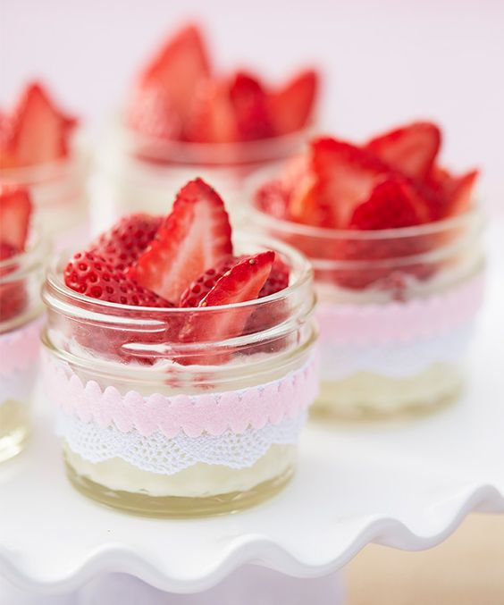 jars with lace and pink ribbons with fresh cream and strawberries are an amazing idea of a wedding dessert