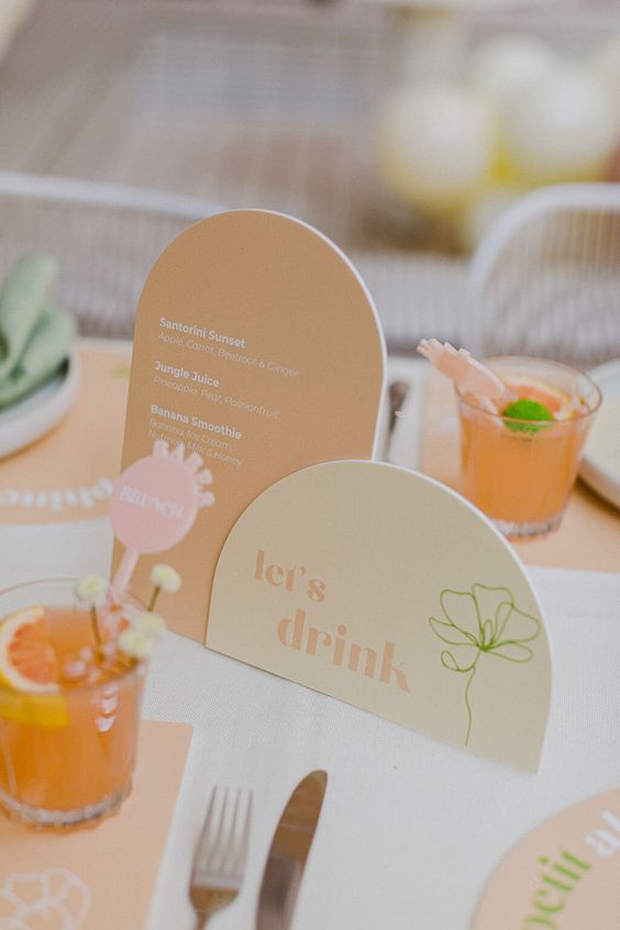 lovely bright wedding signage in light yellow and orange, with orange placemats and some colorful drinks and drink toppers