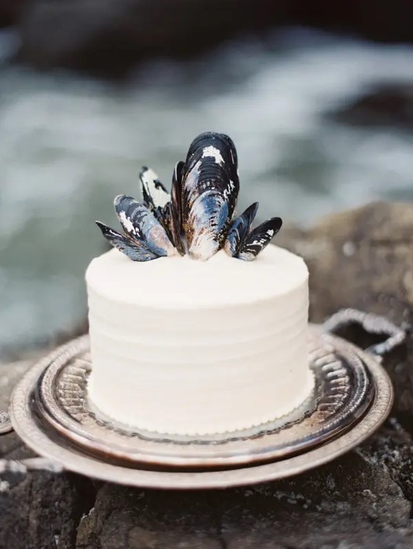 offer your friends a white buttercream wedding cake topped with oyster shells to give it a coastal feel