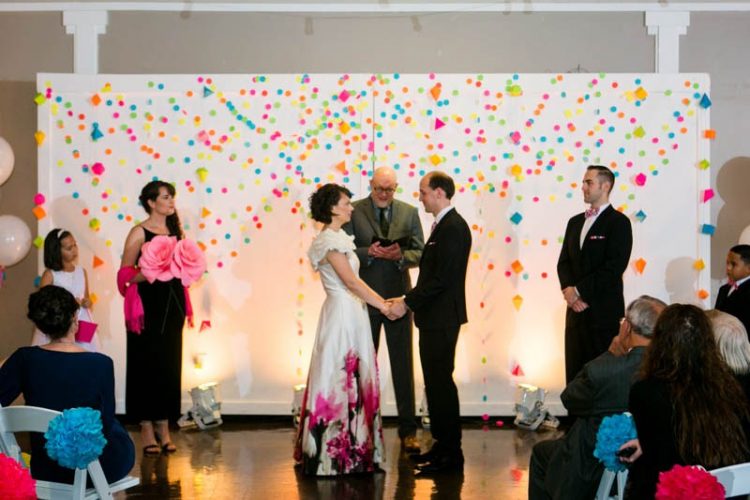 The bride has an oversized paper flower bouquet