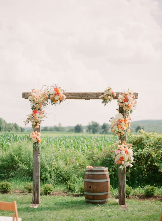 rustic wedding arch with some orange and cream flowers
