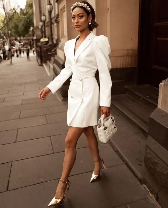 a glam and trendy tuxedo white mini dress with puff sleeves, silver buttons, a white mini bag, a pearl headpiece and silver shoes for a fashion statement