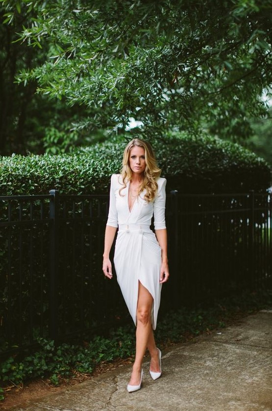 a gorgeous modern white dress with sculptural shoulders, a plunging neckline, a slit plus white heels