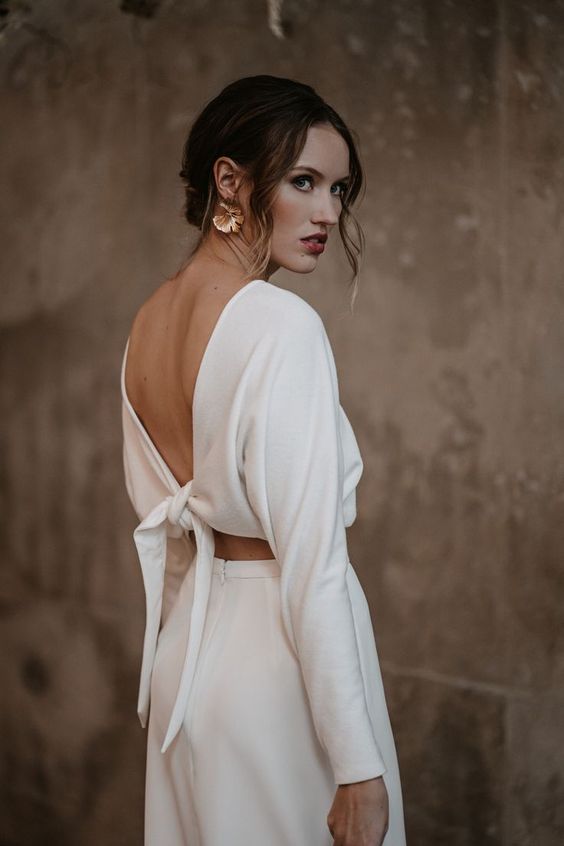 a lovely modern bridal separate with a tied up crop top with long sleeves and a high waisted skirt plus statement earrings