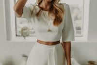 a minimalist look with a plain crop top with short sleeves and high waisted pants with a sash, statement earrings and some more jewelry