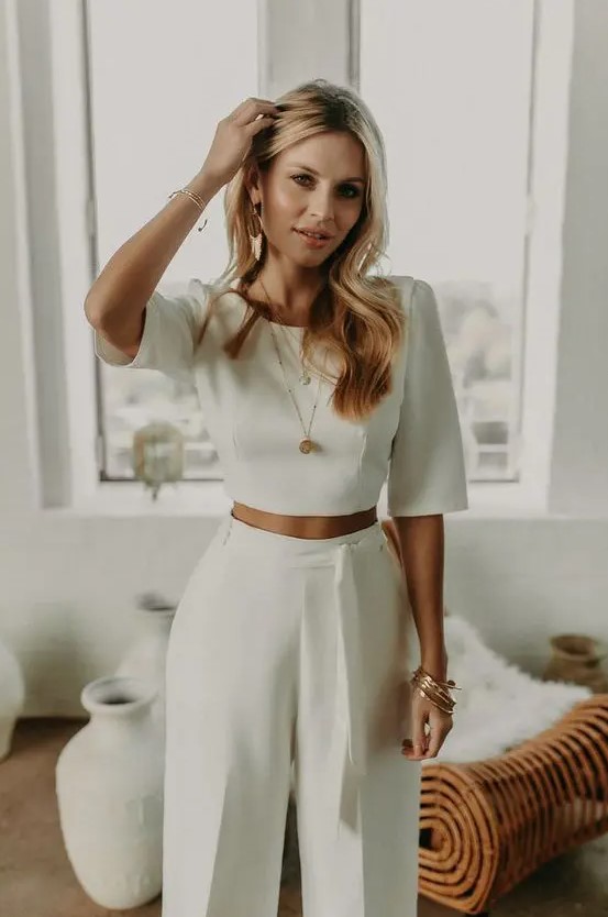a minimalist look with a plain crop top with short sleeves and high waisted pants with a sash, statement earrings and some more jewelry