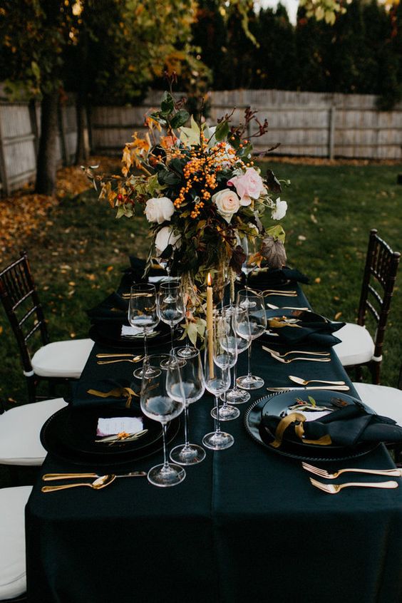 dark fall tablescape with oversized florals, black linens, gold silverware