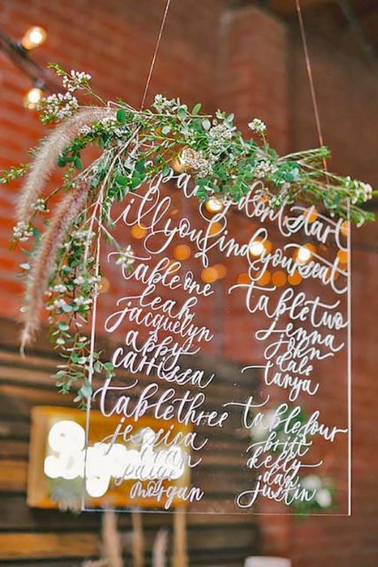 Lucite seating plan decorated by greenery