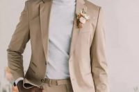 a cool minimalist groom’s look with a tan pantsuit, a neutral turtleneck and a dried flower boutonniere is pure perfection