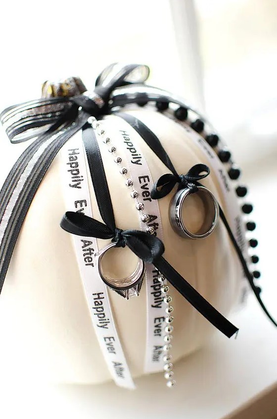a creative alternative to a ring pillow with black and white ribbon and beads and black ribbons holding the rings is cool