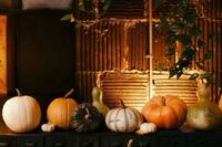a gorgeous rustic fall wedding dessert table with lots of pumpkins and cascading greenery and a cake and a pie is gorgeous