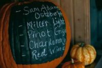 a large pumpkin with a chalkboard element showing the bar menu is a perfect solution for a fall rustic wedding
