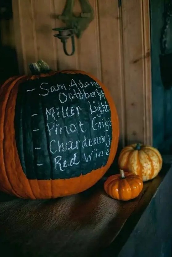 a large pumpkin with a chalkboard element showing the bar menu is a perfect solution for a fall rustic wedding