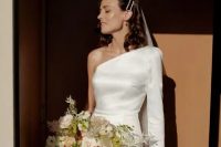 a lovely minimalist bridal look with a one shoulder mini dress with a long sleeve, a long veil and pearl hairpins plus a lovely bouquet