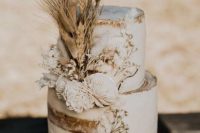 a naked wedding cake with dried grasses and neutral fresh blooms is great for a boho fall wedding