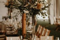 a neutral and chic boho backyard wedding reception space with pretty greenery and pampas grass centerpieces, candles and neutral linens is chic