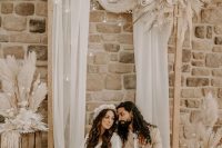 a neutral boho wedding backdrop with dried grasses and leaves, candles in bubbles is a lovely idea for the fall