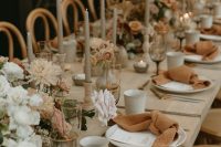 a neutral fall boho wedding tablescape with grey candles, rust napkins, neutral blooms is very inviting and romantic