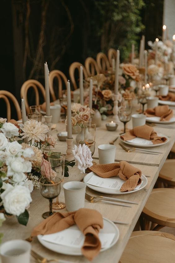 a neutral fall boho wedding tablescape with grey candles, rust napkins, neutral blooms is very inviting and romantic