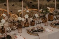 a neutral fall wedding tablescape with neutral flowers, leaves, neutral candles, neutral textiles and bulbs over the table