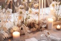 a neutral wedding tablescape with neutral blooms and pillar candles, neutral porcelain and gold cutlery is chic for the fall