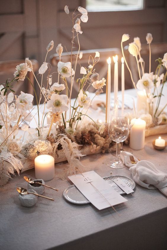 a neutral wedding tablescape with neutral blooms and pillar candles, neutral porcelain and gold cutlery is chic for the fall
