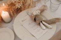 a neutral wedding tablescape with pampas grass and dried leaves, neutral plates and linens is amazing for the fall