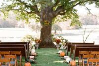 a rustic fall wedding aisle lined up with pumpkins and leaves is a cool and out of the box idea to realize