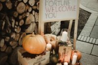 a rustic fall wedding decoration with a sign, some pumpkins and pillar candles plus leaves is a cool solution, and you can DIY it