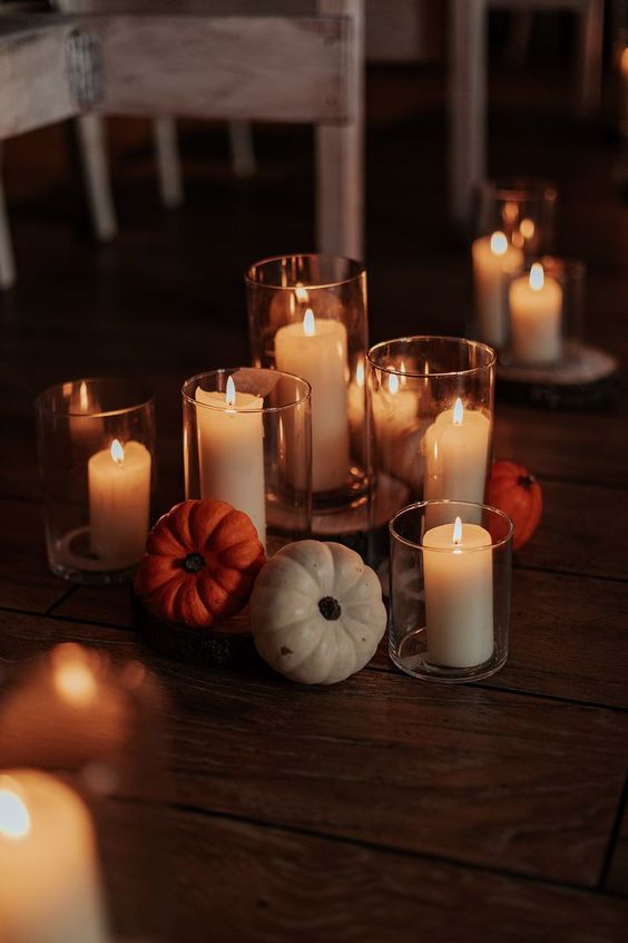 a simple and beautiful rustic wedding centerpiece of pillar candles and some pumpkins is a perfect solution for a fall wedding