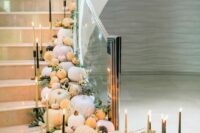 a wedding staricase decorated with pumpkins, eucalyptus, tall and thin candles is adorable and very sophisticated