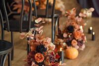 an elegant fall wedding ceremony space with bold blooms, black pillar candles and gilded pumpkins is amazing