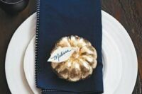 an elegant place setting with white porcelain, a navy napkin and a tiny gilded pumpkin with a card