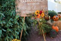 beautiful fall wedding decor with a sign done with bright fall blooms, potted flowers and pumpkins is amazing for a fall wedding