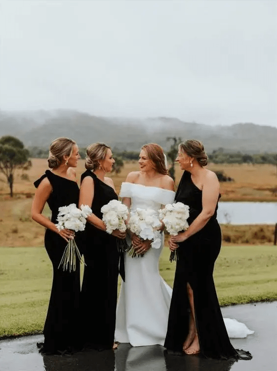 elegant black one shoulder bridesmaid dresses with bows on the shoulders, slits and trains for a formal wedding