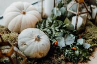 fall wedding decor with white pumpkins on moss, greenery, berries and candle lanterns is amazing